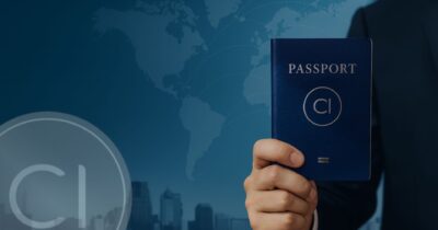 Hand holding a second passport in front of a world map background